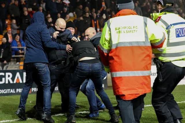 Rival fans fight on the pitch as stewards and police move in