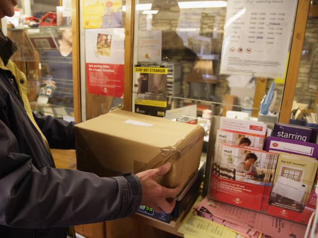 Customers weigh packages at the post office.