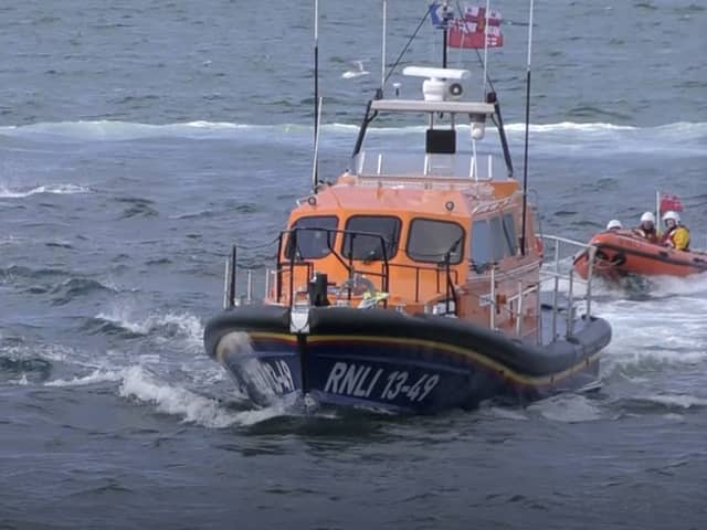 Dolphins swim alongside RNLI lifeboat in Whitby, North Yorkshire. 