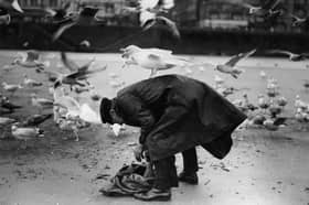 17th January 1934:  A member of the Blackpool lifeboat crew takes it upon himself to feed the local seagulls during the winter months.  (Photo by Fox Photos/Getty Images)