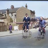Two men riding a bone-shaker bicycle and a penny farthing on Vicarage Lane, with the Oxford Garage on Waterloo Road in the background. The photograph was probably taken in the 1950s