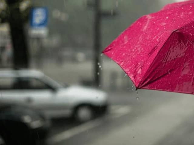 Red umbrella in the rain, as yellow weather alert is in place across Lancashire