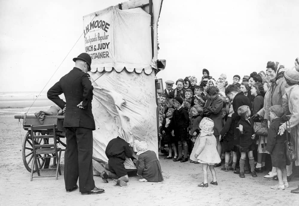 What a great shot this is - a couple of cheeky youngsters are caught taking a peek behind the scenes of this Punch and Judy show on Blackpool beach
