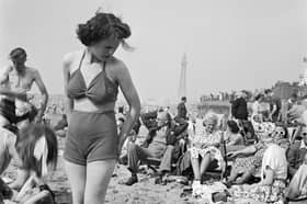 A young woman in a knitted bathing costume stands on the beach in the midst of the crowds of holidaymakers, Blackpool, c1946-c1955. Blackpool Tower is visible in the background. (Photo by English Heritage/Heritage Images/Getty Images)