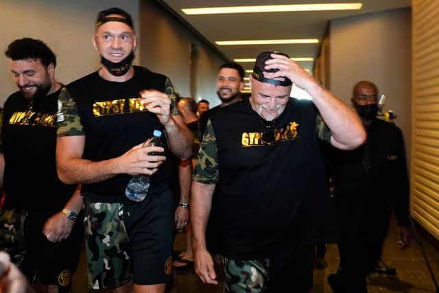 Tyson looking slightly embarassed as he walks with his father who appears to be smiling.  Credi: PA