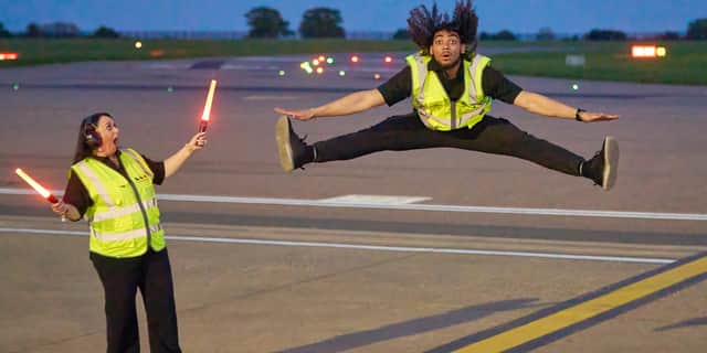 Airport ground handlers perform lively dance routine on runway.