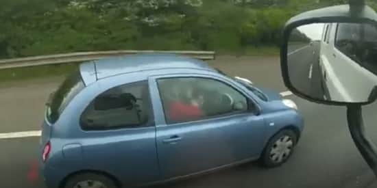 Woman applies make-up while driving along the motorway.