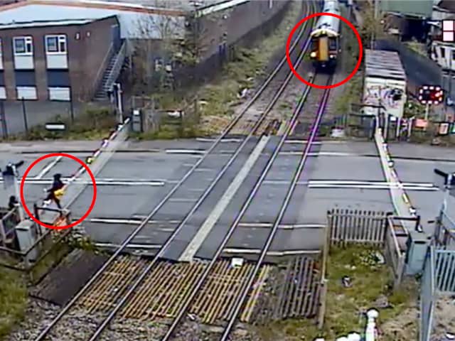 Man climbs train crossing barrier and strolls across tracks moments before a high speed train travels through at Station Road in Langley Green, Oldbury, West Midlands, on April 27, 2024.