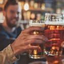 Friends drinking pints and toasting beer at a pub. Image: Sasint/stock.adobe