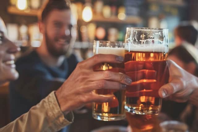 Friends drinking pints and toasting beer at a pub. Image: Sasint/stock.adobe