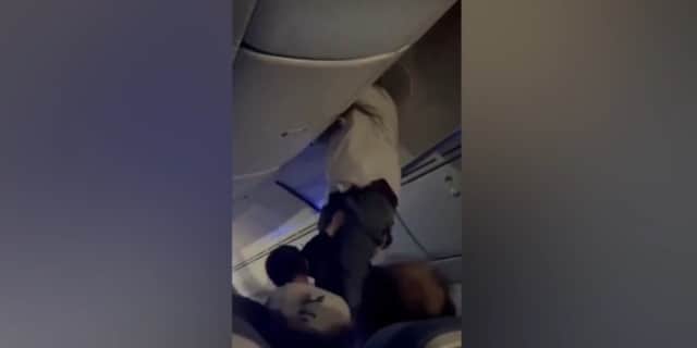 Passengers help man from overhead bin after 'strong turbulence'.