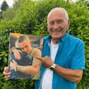 Tommy Cannon holds a photo of himself hugging Robbie Williams.
