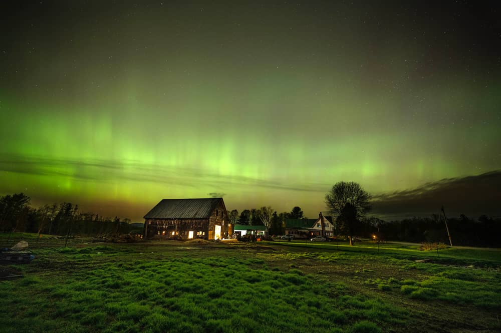 The northern lights fill the sky with green ribbons of electrical charged particles over a barn (Photo by Michael Seamans/Getty Images)