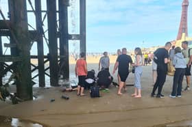 Crowds below Central Pier in Blackpool trying to help teen who fell onto the beach through boards above