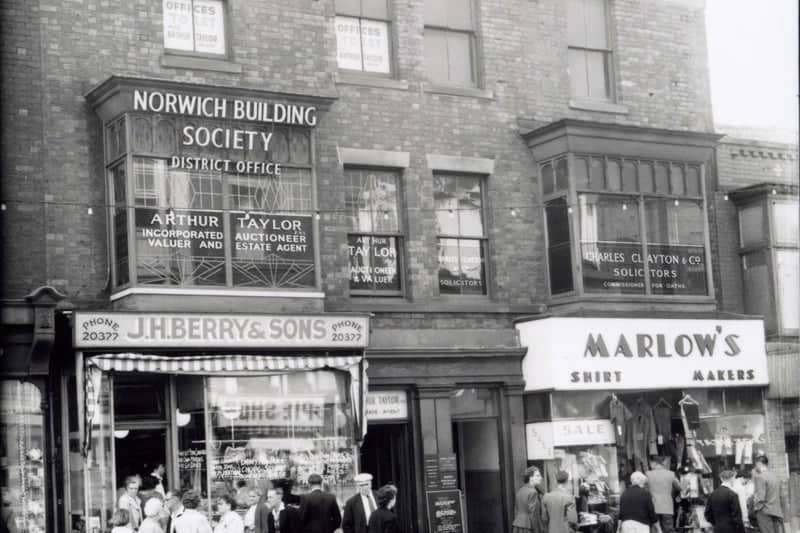 Talbot Road, Blackpool - south side between Abingdon Street and Topping Street. J.H. Berry & Son pork butcher and pie shop. Marlow's outfitters, Norwich Building Society, Charles Clayton and Co solicitors