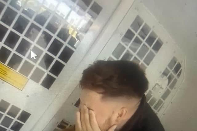 Sat in a police van he places his hands over his face and appears to cry.