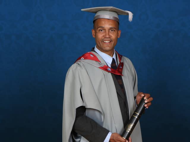 Clarke Carlisle holding his Honorary Fellowship from the University of Central Lancashire.