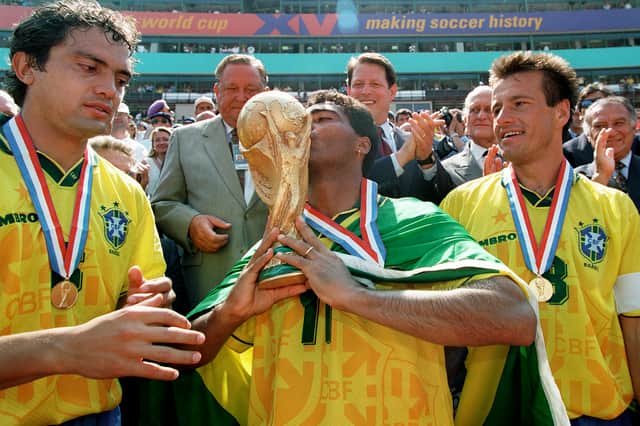 Brazilian forward Romario kisses the FIFA World Cup trophy 1994 as his teammates Branco (left) and Dunga look on. Brazil defeated Italy in the final on penalties when the tournament was last held in the United States