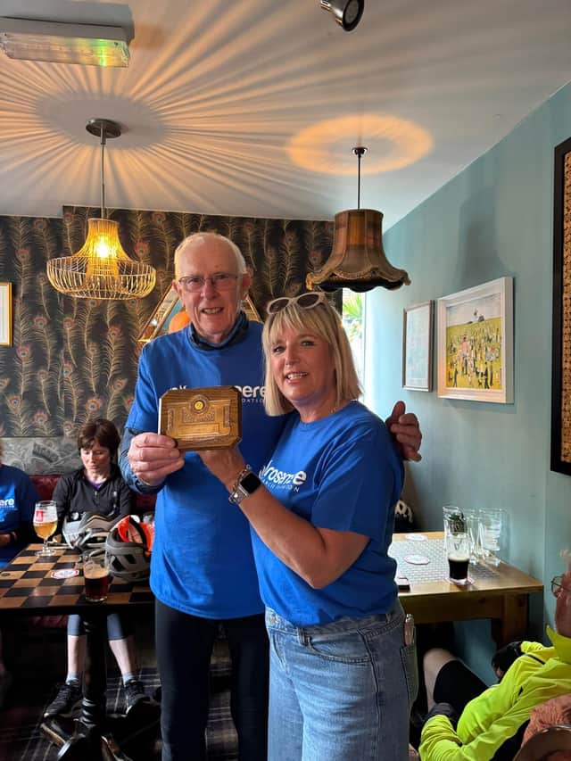 Cyclist John Smith is presented with his oldest Taps finisher award at the age of 81 by marshal Helen Kirkman