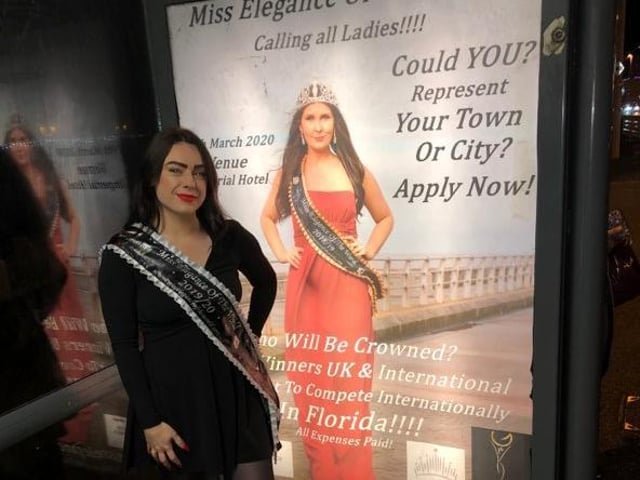 Bethan Mcauley, a contestant in this year's competition Miss Elegance of the World, standing next to a poster at a Blackpool bus stop