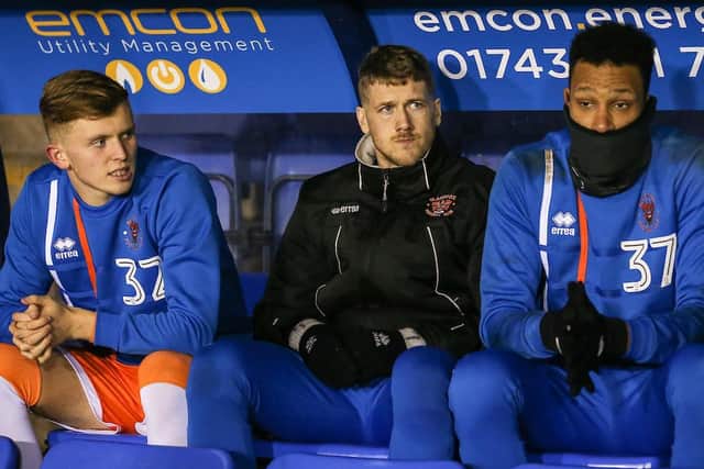 Roache sitting on the bench alongside Jim McAlister and Christoffer Mafoumbi during an EFL Trophy fixture