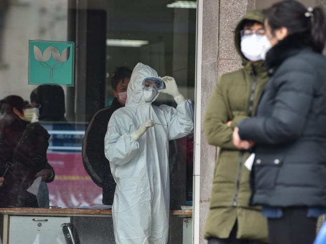 A nurse wearing protective clothing to help stop the spread of a deadly virus which began in the city, looks at a thermometer at the Wuhan Fifth Hospital in Wuhan (Photo by HECTOR RETAMAL/AFP via Getty Images)