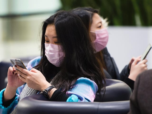 People wear masks following the outbreak of a new virus as people arrive from the International terminal at Toronto Pearson International Airport in Toronto on Saturday, Jan. 25, 2020.