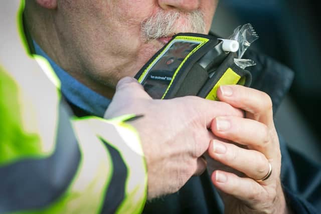 A driver blows into a PSNI Road Policing officers' breathalyser during a random drink driving checkpoint