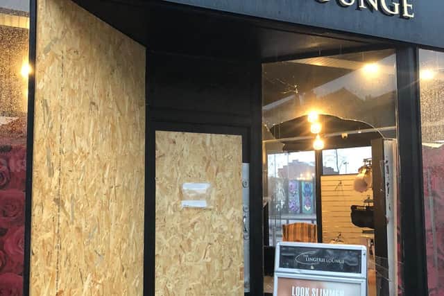 The boarded up windows from the previous burglary at the Lingerie Lounge with the latest broken window where crooks have got is and stole stock for the third time in three weeks
