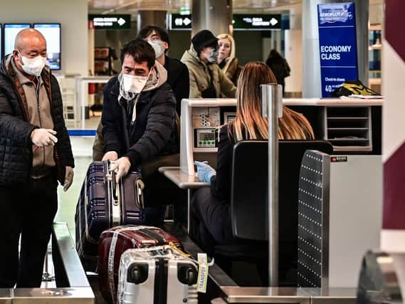 Passengers wearing a respiratory mask check in at Milan-Malpensa airport in Ferno, northwest of Milan, in one of Italy's quarantine red zones (Photo by MIGUEL MEDINA/AFP via Getty Images)