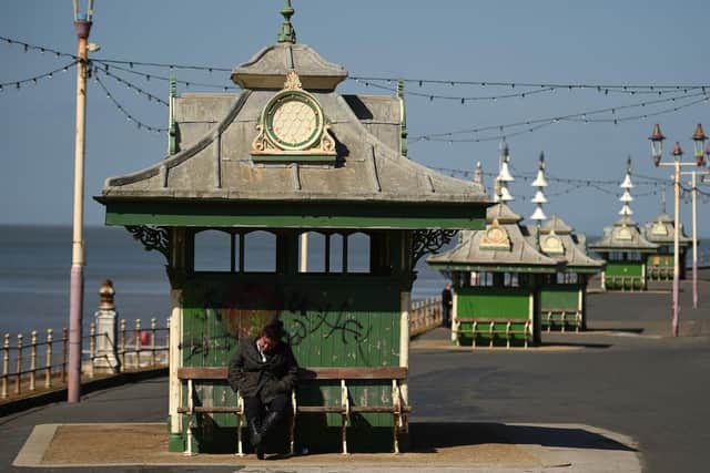 A woman sits on a bench in the spring sunshine on the coast in Blackpool during the nationwide lockdown (Photo by OLI SCARFF/AFP via Getty Images)