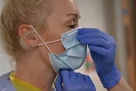 A member of clinical staff adjusts her mask as she wears Personal Protective Equipment (PPE) working in the Covid Recovery Ward