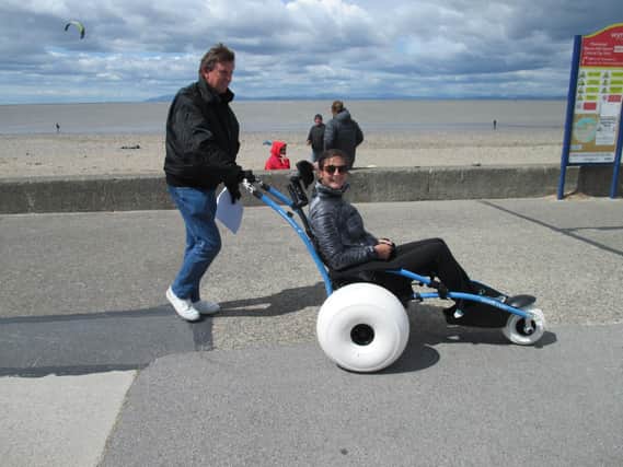 Mick Gray, chairman of the Fleetwood Beach Wheelchair Group,  pushes a volunteer in the Hippocampe Chair on the seafront.