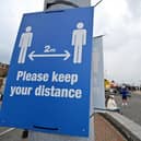 Signs ask visitors to adhere to the British government's current social distancing guidelines and stay two meters apart