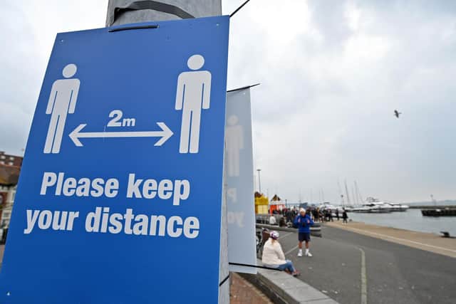 Signs ask visitors to adhere to the British government's current social distancing guidelines and stay two meters apart