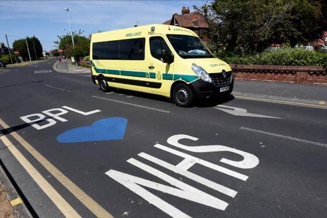 An ambulance driving past a 'Blackpool loves NHS' painting on the road outside Blackpool Victoria Hospital during the Covid-19 pandemic