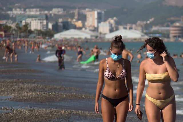 Women wearing face masks walk along La Misericordia Beach in Malaga (Photo by JORGE GUERRERO/AFP via Getty Images)