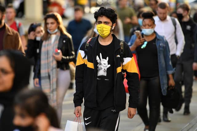 Pedestrians, some wearing a face mask or covering due to the COVID-19 pandemic, walk in Manchester
