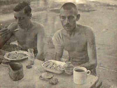Badly treated POWs finally tucking into some real food after liberation