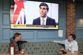 Drinkers watch chancellor Rishi Sunak on television news