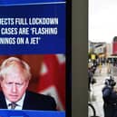 A news display features Britain's Prime Minister Boris Johnson as shoppers make their way along the streets of Manchester