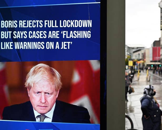 A news display features Britain's Prime Minister Boris Johnson as shoppers make their way along the streets of Manchester