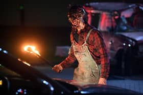 An actor dressed as a character from a horror movie scares people as they watch a horror film at a temporary drive in cinema in Manchester