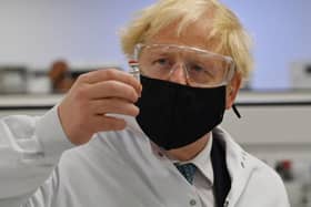 Britain's Prime Minister Boris Johnson poses for a photograph with a vial of the AstraZeneca/Oxford University COVID-19 candidate vaccine, known as AZD1222, at Wockhardt's pharmaceutical manufacturing facility in Wrexham, north Wales, on November 30, 2020.