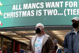 People wearing face masks walk past a sign on Market Street, Manchester