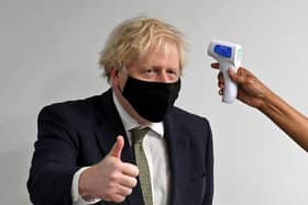 Prime Minister Boris Johnson gives a thumbs up as he has his temperature checked during a visit to Chase Farm Hospital in north London