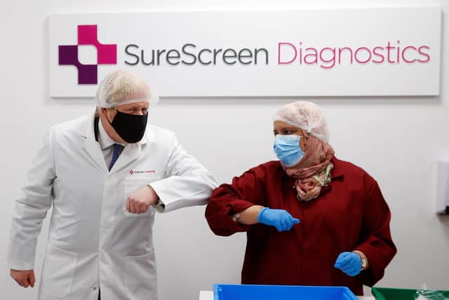 Prime Minister Boris Johnson bumps elbows with a staff member during a Covid-19 related visit to SureScreen Diagnostics in Derby