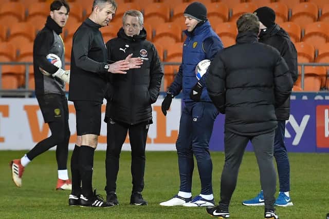 Referee Christopher Sarginson deliberates with Blackpool boss Neil Critchley