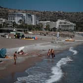 Tourists walk the beach in front of hotels on the Aegean island of Rhodes