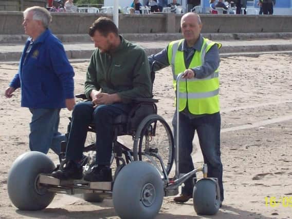 Trustee Malcolm Lewis (right) with a beach wheelchair at Fleetwood